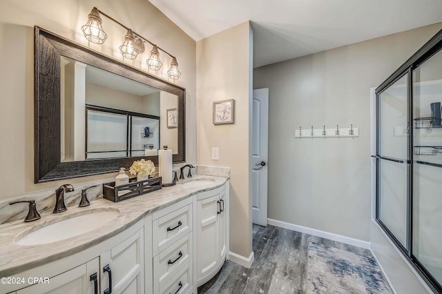 bathroom with bath / shower combo with glass door, vanity, and wood-type flooring