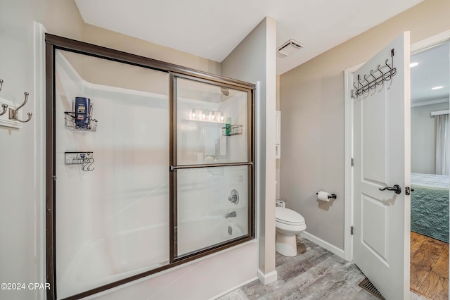 bathroom with hardwood / wood-style floors, toilet, and enclosed tub / shower combo