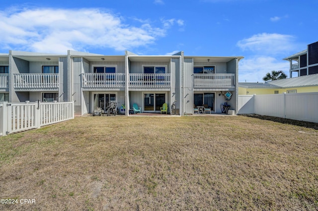 rear view of house featuring a patio area, a balcony, and a lawn