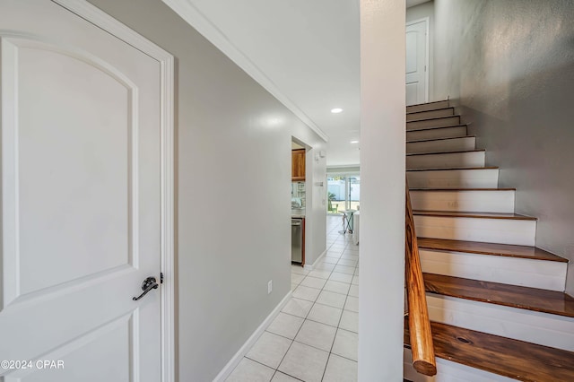 staircase with tile patterned flooring and ornamental molding