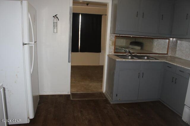 kitchen with sink, gray cabinets, white fridge, and dark wood-type flooring