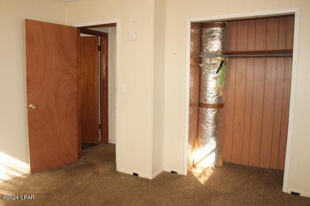 unfurnished bedroom featuring a closet and dark colored carpet