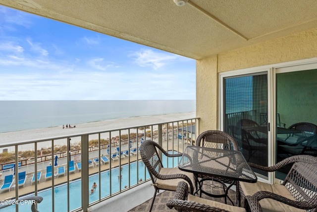 balcony with a view of the beach, a community pool, and a water view