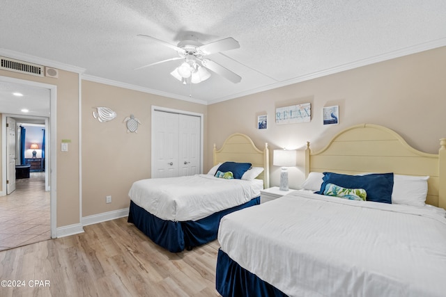 bedroom with a closet, ceiling fan, light hardwood / wood-style flooring, a textured ceiling, and ornamental molding