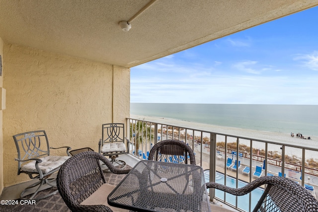 balcony with a water view, a community pool, and a view of the beach