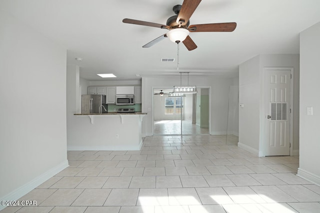 unfurnished living room featuring ceiling fan, light tile floors, and sink