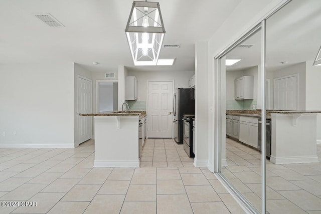 kitchen with light tile floors, a kitchen bar, electric stove, and dark stone counters