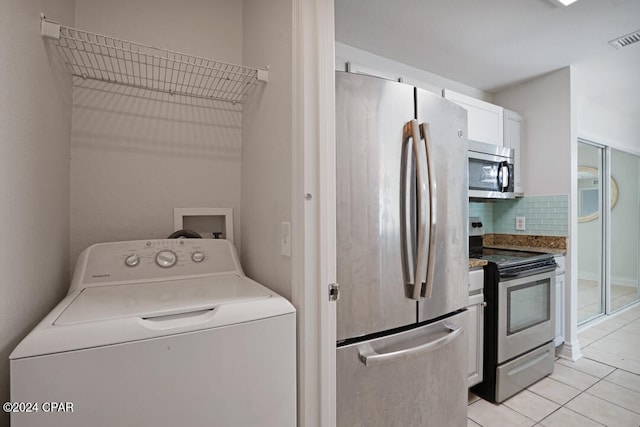 laundry room with washer / dryer and light tile floors