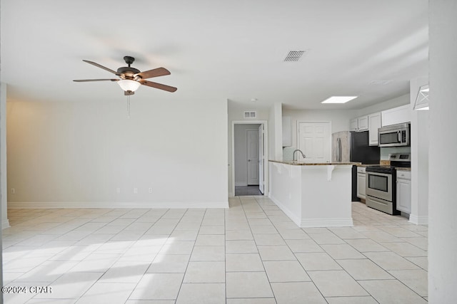 kitchen with white cabinets, light tile floors, ceiling fan, and appliances with stainless steel finishes