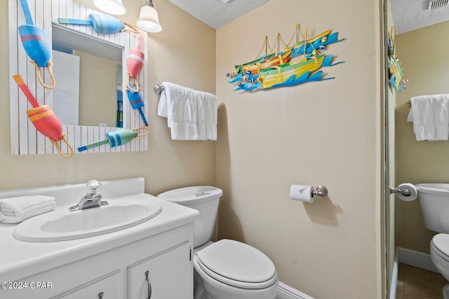 bathroom with a textured ceiling, oversized vanity, and toilet