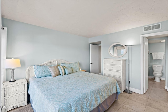 bedroom with light tile floors and ensuite bathroom