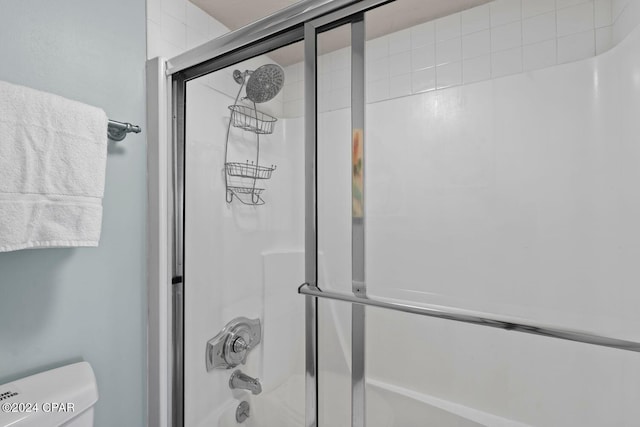 bathroom with combined bath / shower with glass door and toilet