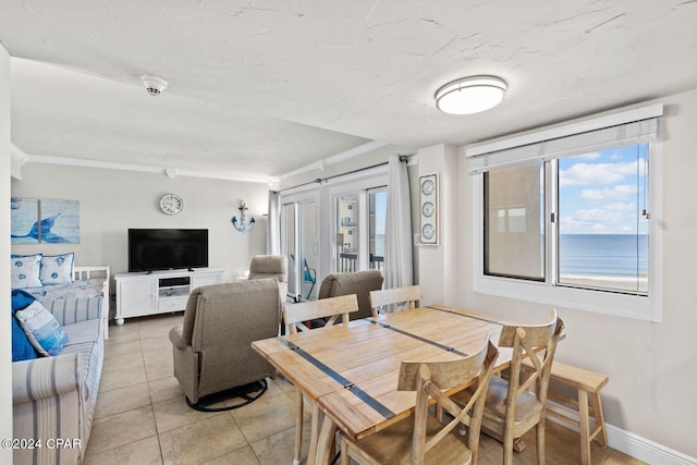 dining room with crown molding, a water view, and tile floors