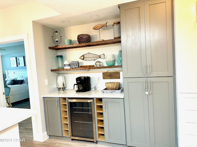 bar with light wood-type flooring, wine cooler, and a dry bar