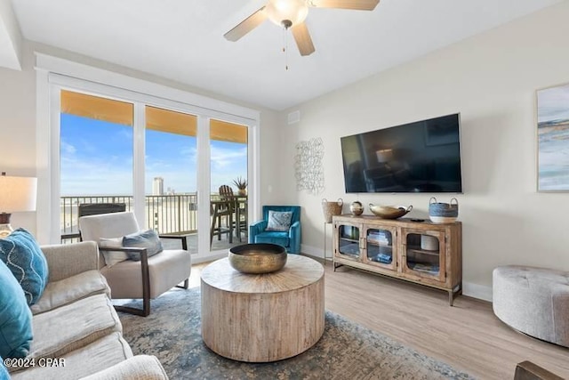 living room with wood finished floors, a ceiling fan, and baseboards