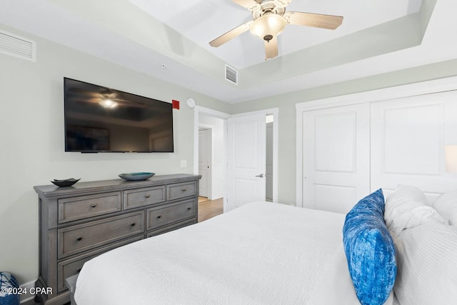 bedroom featuring a ceiling fan, a raised ceiling, visible vents, and a closet