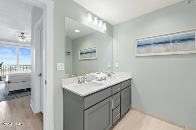 bathroom featuring double vanity, ensuite bath, a ceiling fan, and a sink