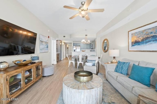 living room with light wood finished floors and ceiling fan with notable chandelier