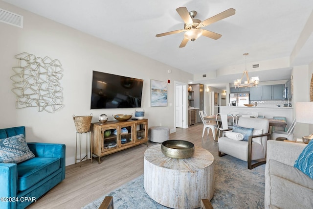 living area with light wood-style flooring, visible vents, and ceiling fan with notable chandelier