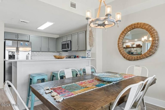 dining space featuring a chandelier, dark wood-style floors, visible vents, and baseboards