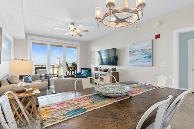 dining room with ceiling fan with notable chandelier and light wood-style floors