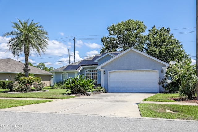 ranch-style house with a garage, solar panels, and a front lawn