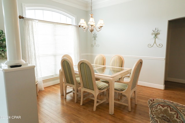 dining room featuring a healthy amount of sunlight, ornamental molding, an inviting chandelier, and hardwood / wood-style floors