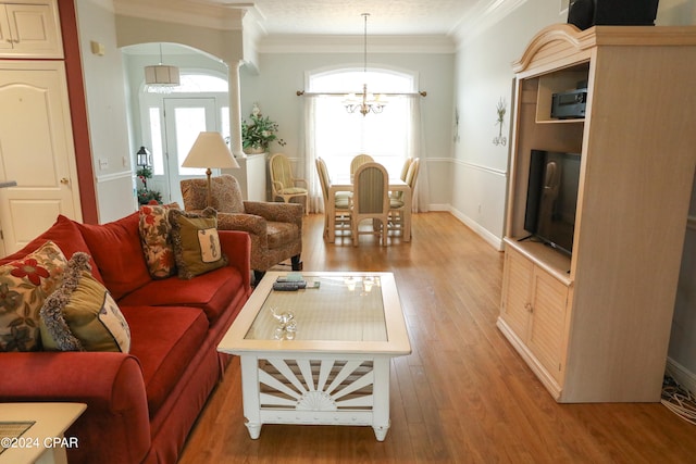 living room with crown molding, hardwood / wood-style flooring, and a chandelier