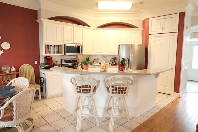 kitchen with stainless steel appliances, a center island, light hardwood / wood-style flooring, and crown molding