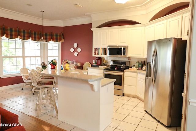 kitchen with a kitchen breakfast bar, stainless steel appliances, crown molding, and light tile flooring