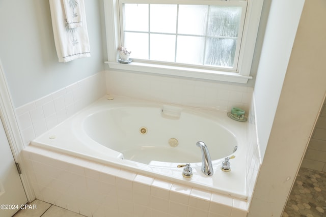 bathroom featuring a healthy amount of sunlight, tiled bath, and tile floors