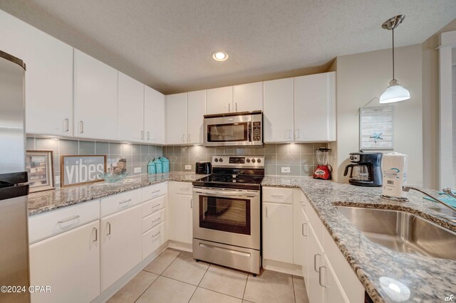 kitchen featuring sink, stainless steel appliances, light tile patterned floors, decorative backsplash, and white cabinets