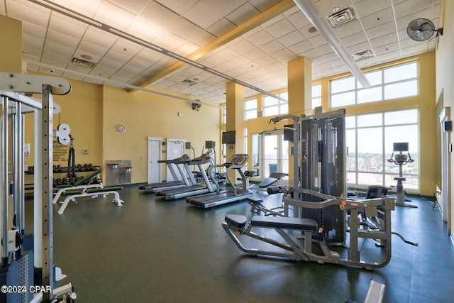 workout area featuring a paneled ceiling, a high ceiling, and a wealth of natural light