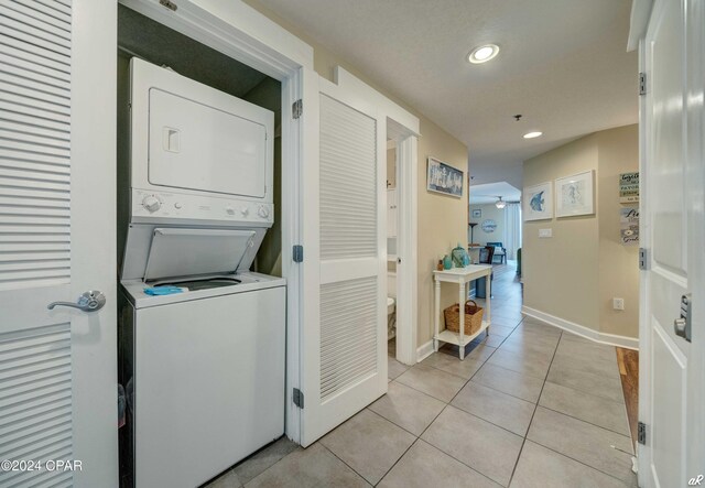 laundry room featuring ceiling fan, light tile patterned flooring, and stacked washing maching and dryer