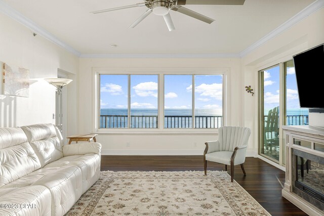 living room with ceiling fan, a fireplace, dark wood-type flooring, and ornamental molding