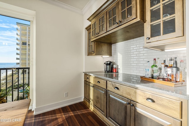 kitchen featuring decorative backsplash, ornamental molding, a water view, dark wood-type flooring, and dark stone countertops