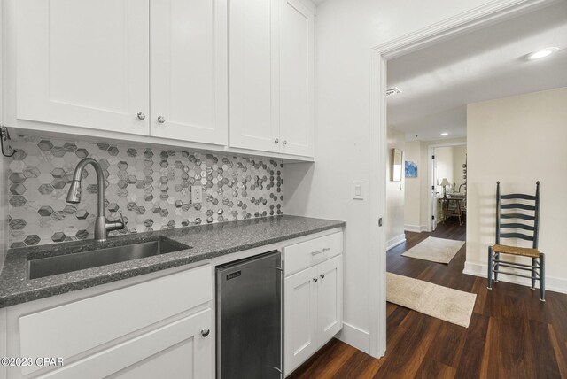 kitchen with stainless steel dishwasher, dark wood-type flooring, tasteful backsplash, and white cabinets