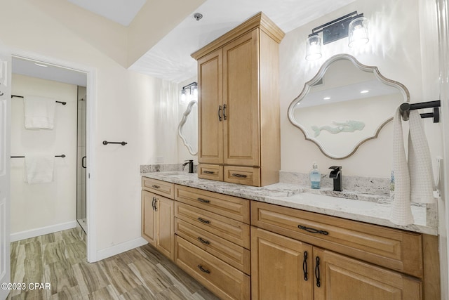 bathroom with hardwood / wood-style flooring, dual bowl vanity, and a shower with door