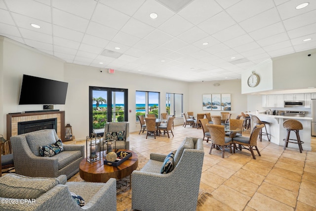 living room with french doors, a paneled ceiling, and light tile patterned floors