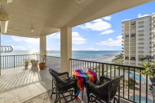 balcony featuring a community pool, a view of the beach, and a water view