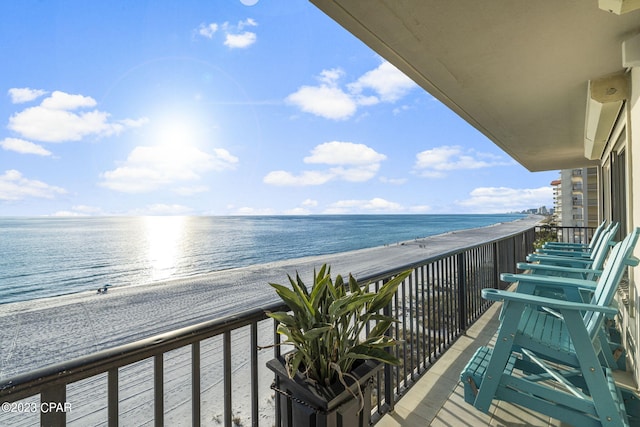 balcony featuring a view of the beach and a water view