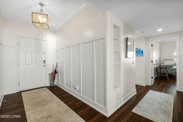 foyer featuring dark hardwood / wood-style floors, a notable chandelier, and ornamental molding