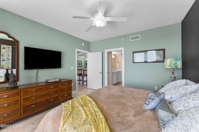 bedroom featuring a textured ceiling, light wood-type flooring, ensuite bathroom, and ceiling fan