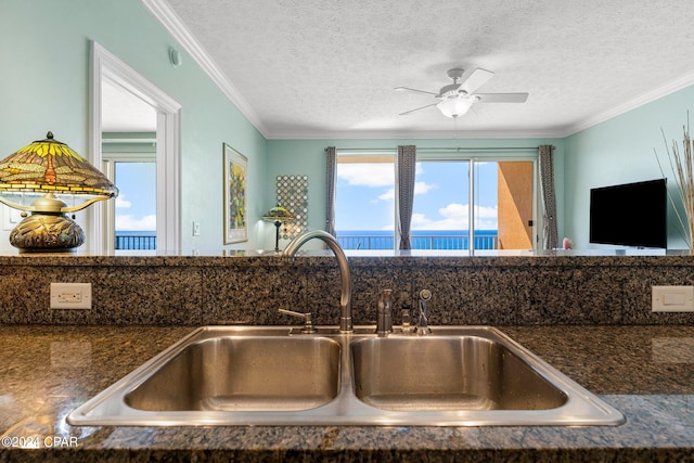 kitchen with ceiling fan, sink, a textured ceiling, and ornamental molding