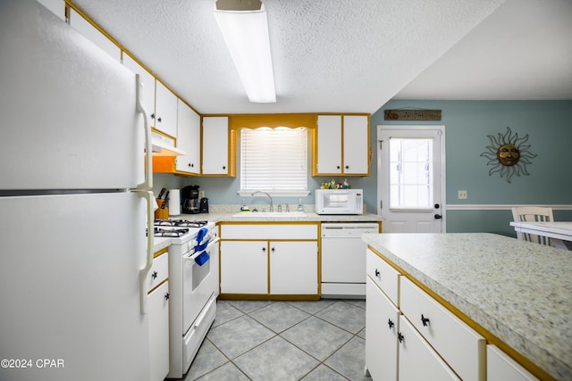 kitchen with white cabinetry, white appliances, fume extractor, sink, and light tile floors