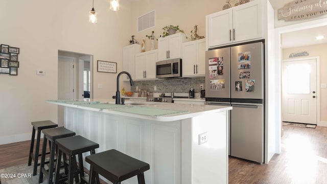 kitchen with a center island with sink, white cabinetry, dark wood-type flooring, and stainless steel appliances