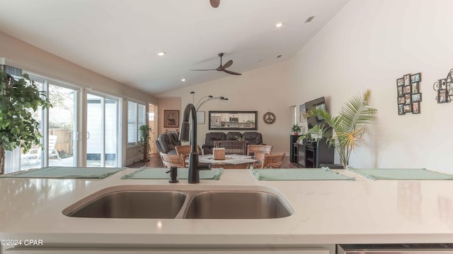 kitchen featuring light stone counters, vaulted ceiling, ceiling fan, and sink