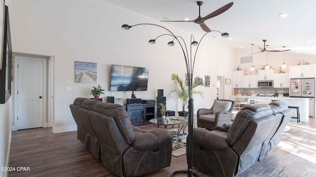 living room featuring dark hardwood / wood-style floors, ceiling fan, and a towering ceiling