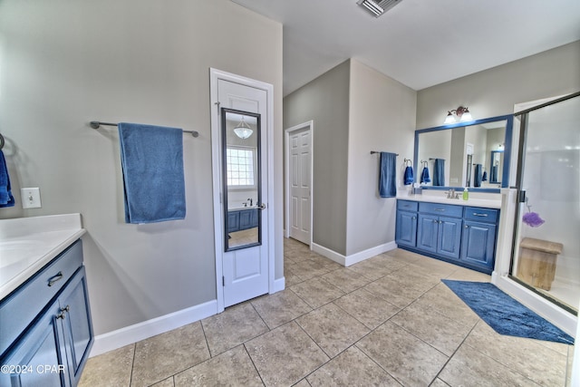 full bath featuring two vanities, a sink, a shower stall, tile patterned flooring, and baseboards