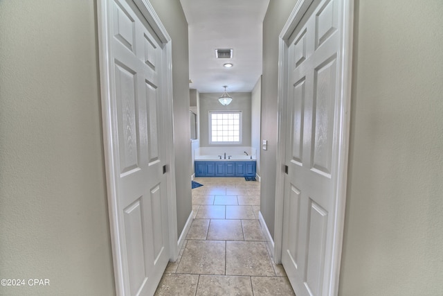 hallway with light tile patterned floors, baseboards, and visible vents